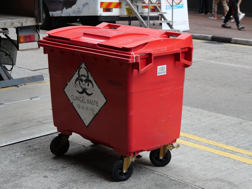 A large outdoor area covered with a dense pile of mixed waste and rubbish, including plastic bottles, paper, cardboard, and other household waste Materials such as crumpled paper, plastic packaging, a